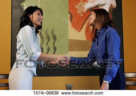Stock Photo - Side profile of two businesswomen shaking hands. Fotosearch