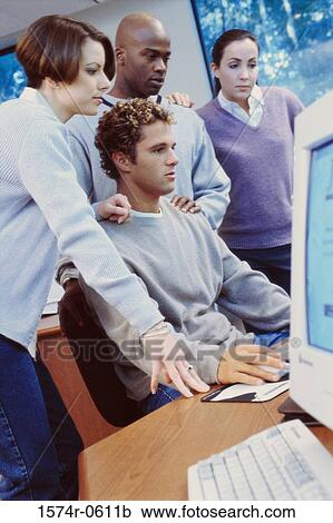 Stock Image - Side profile of two young men and two young women using a computer. Fotosearch