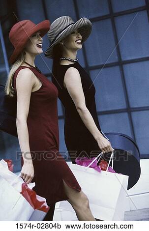 Side profile of two young women walking with shopping bags View Large Photo Image Stock Image - Side profile of two young women walking with shopping bags. Fotosearch