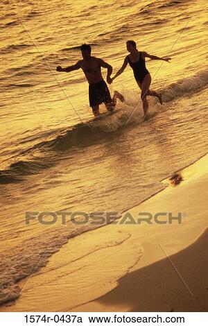 Silhouette of a young couple running on the beach View Large Photo Image Stock Image - Silhouette of a young couple running on the beach. Fotosearch