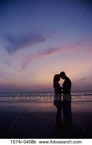 Silhouette of a young couple standing on the beach View Large Photo Image Stock Image - Silhouette of a young couple standing on the beach. Fotosearch