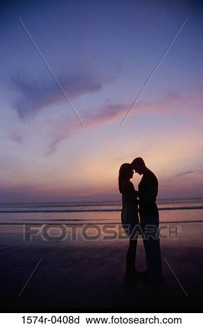 Silhouette of a young couple standing on the beach View Large Photo Image Stock Image - Silhouette of a young couple standing on the beach. Fotosearch