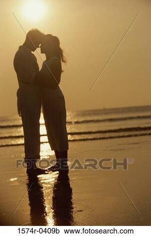 Silhouette of a young couple standing on the beach View Large Photo Image Stock Image - Silhouette of a young couple standing on the beach. Fotosearch