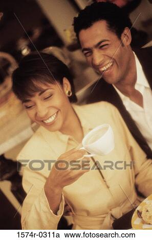 Stock Image - Smiling young couple holding cups of coffee. Fotosearch