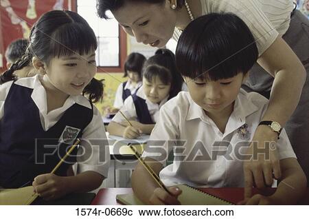 Stock Image - Teacher helping students in class. Fotosearch
