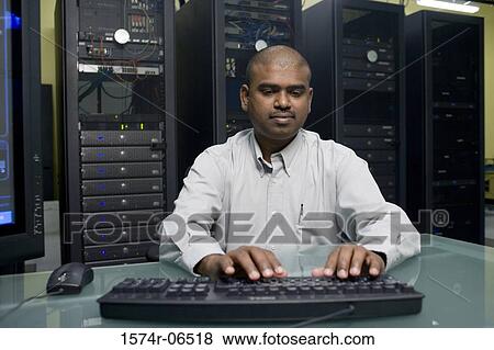 Technician using a computer in a server room View Large Photo Image Stock Photo - Technician using a computer in a server room. Fotosearch