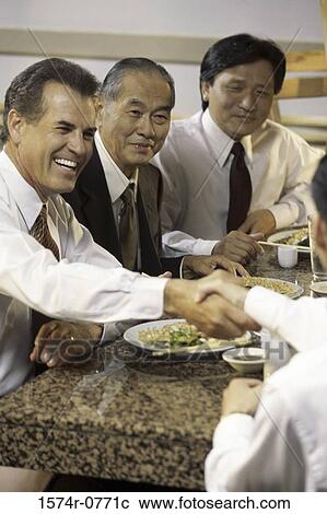Stock Image - Three business executives seated at a restaurant. Fotosearch