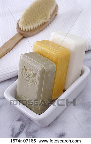 Stock Photography - Three soaps in a soap dish with a brush and towel. Fotosearch