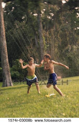 Two boys playing in a water sprinkler View Large Photo Image Stock Image - Two boys playing in a water sprinkler. Fotosearch