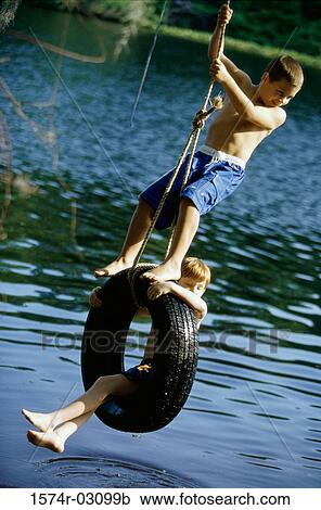 Two boys playing on a tire swing View Large Photo Image Stock Image - Two boys playing on a tire swing. Fotosearch