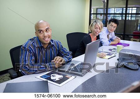 Two businessmen and a businesswoman sitting in a conference room View Large Photo Image Stock Image - Two businessmen and a businesswoman sitting in a conference room. Fotosearch
