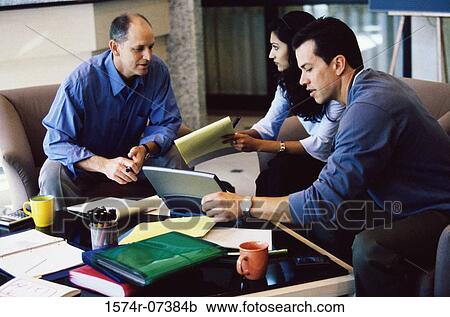 Stock Image - Two businessmen and a businesswoman discussing. Fotosearch