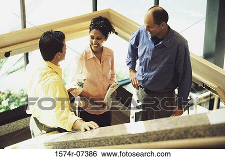 Stock Photograph - Two businessmen and a businesswoman discussing on stairs. Fotosearch