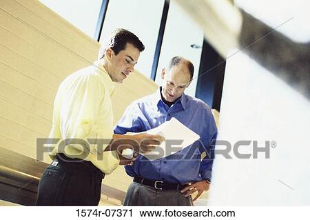 Two businessmen discussing a report View Large Photo Image Stock Image - Two businessmen discussing a report. Fotosearch