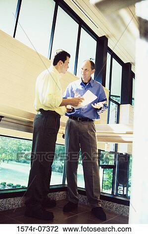 Two businessmen discussing a report View Large Photo Image Stock Image - Two businessmen discussing a report. Fotosearch