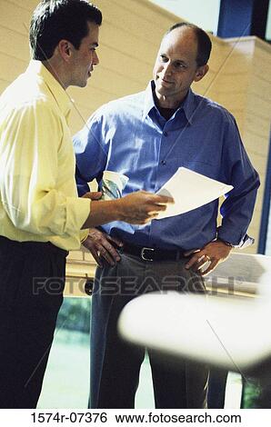 Two businessmen discussing a report View Large Photo Image Stock Photograph - Two businessmen discussing a report. Fotosearch