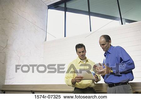 Two businessmen discussing a report View Large Photo Image Stock Photography - Two businessmen discussing a report. Fotosearch