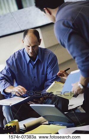 Stock Image - Two businessmen discussing in an office. Fotosearch
