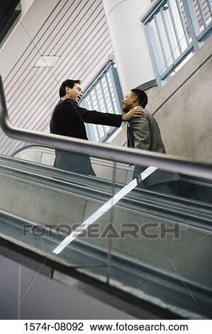 Two businessmen on an escalator View Large Photo Image Stock Image - Two businessmen on an escalator. Fotosearch