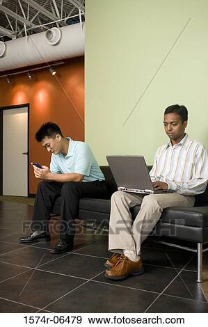 Two businessmen sitting on a couch in an office View Large Photo Image Stock Photo - Two businessmen sitting on a couch in an office. Fotosearch
