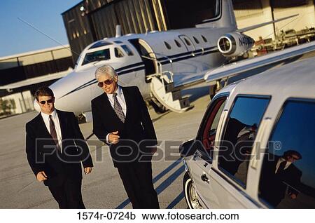 Stock Image - Two businessmen walking in an airport. Fotosearch