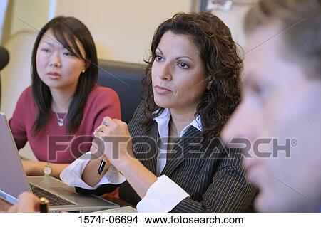 Picture - Two businesswomen and a businessman sitting in a conference room. Fotosearch