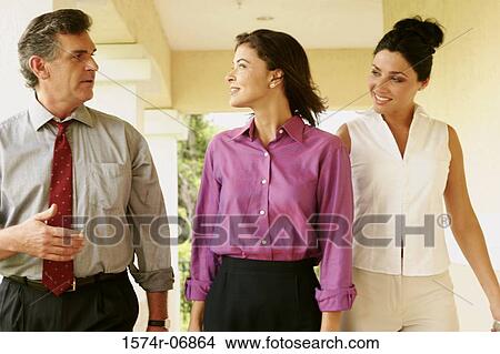Picture - Two businesswomen and a businessman walking in corridor. Fotosearch