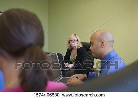 Two businesswomen and a businessman sitting in a conference room View Large Photo Image Stock Image - Two businesswomen and a businessman sitting in a conference room. Fotosearch