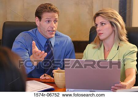 Stock Image - Two businesswomen and a businessman sitting in a conference room. Fotosearch