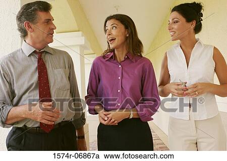 Two businesswomen and a businessman walking in corridor View Large Photo Image Stock Image - Two businesswomen and a businessman walking in corridor. Fotosearch