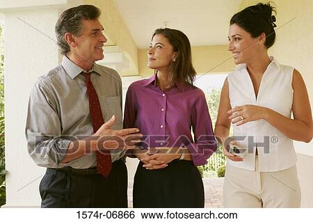 Stock Photograph - Two businesswomen and a businessman walking in corridor. Fotosearch