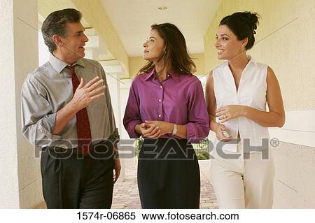 Stock Photography - Two businesswomen and a businessman walking in corridor. Fotosearch