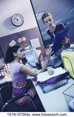 Stock Image - Two businesswomen in an office talking. Fotosearch