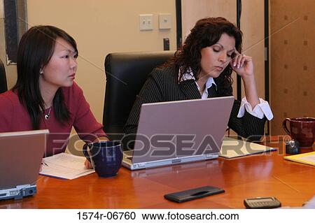 Stock Image - Two businesswomen sitting in a conference room. Fotosearch