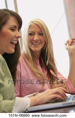 Two businesswomen working on a laptop View Large Photo Image Stock Image - Two businesswomen working on a laptop. Fotosearch