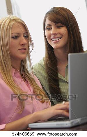 Stock Photo - Two businesswomen working on a laptop. Fotosearch