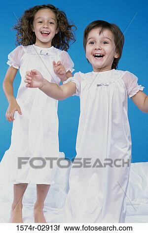 Two girls jumping on a bed View Large Photo Image Stock Image - Two girls jumping on a bed. Fotosearch
