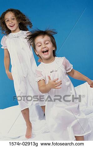 Two girls jumping on a bed View Large Photo Image Stock Image - Two girls jumping on a bed. Fotosearch