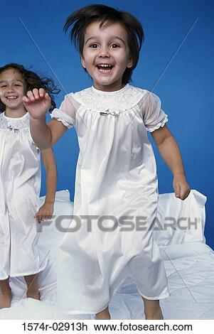 Two girls jumping on a bed View Large Photo Image Stock Image - Two girls jumping on a bed. Fotosearch