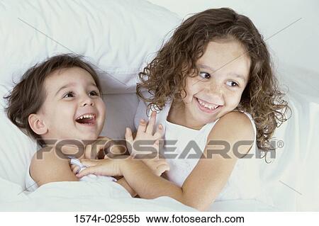 Stock Image - Two girls playing on a bed. Fotosearch