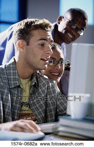 Stock Image - Two young men and a young woman studying together. Fotosearch