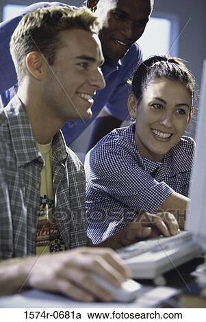 Two young men and a young woman using a computer View Large Photo Image Stock Image - Two young men and a young woman using a computer. Fotosearch