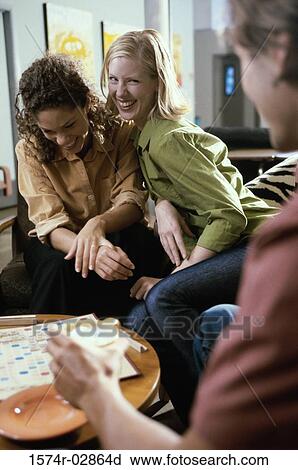 Stock Image - Two young women and a young man playing scrabble. Fotosearch