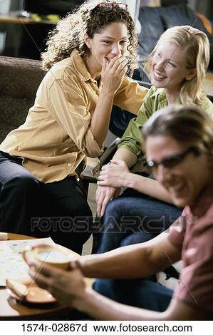 Stock Image - Two young women and a young man sitting in a cafeteria. Fotosearch