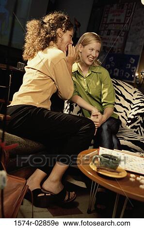 Two young women sitting in a cafeteria whispering View Large Photo Image Stock Image - Two young women sitting in a cafeteria whispering. Fotosearch