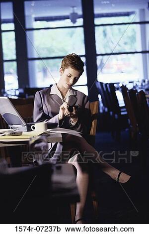 Woman sitting in a restaurant using a hand held device View Large Photo Image Stock Image - Woman sitting in a restaurant using a hand held device. Fotosearch