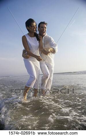 Young couple holding each other on the beach View Large Photo Image Stock Image - Young couple holding each other on the beach. Fotosearch