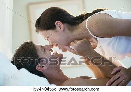 Young couple lying down on a bed smiling View Large Photo Image Stock Image - Young couple lying down on a bed smiling. Fotosearch