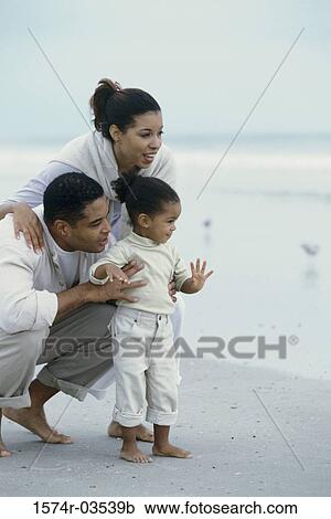 Stock Image - Young couple on the beach with their daughter. Fotosearch