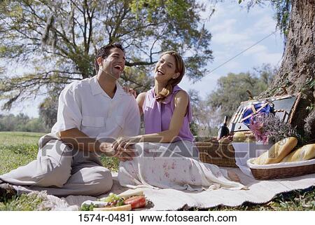 Stock Image - Young couple sitting together at a picnic. Fotosearch